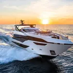 Transistor gracefully cutting through waves at sunset, showcasing its sleek profile and luxury design.