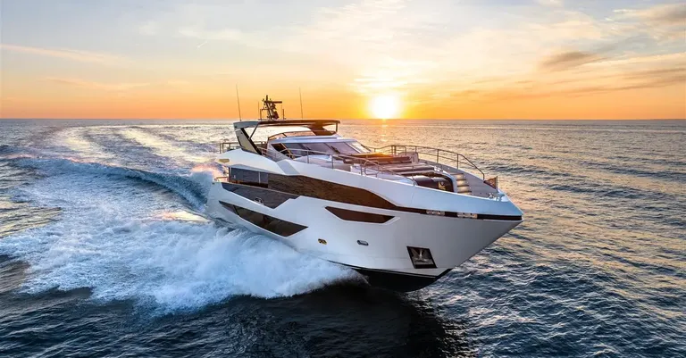Transistor gracefully cutting through waves at sunset, showcasing its sleek profile and luxury design.