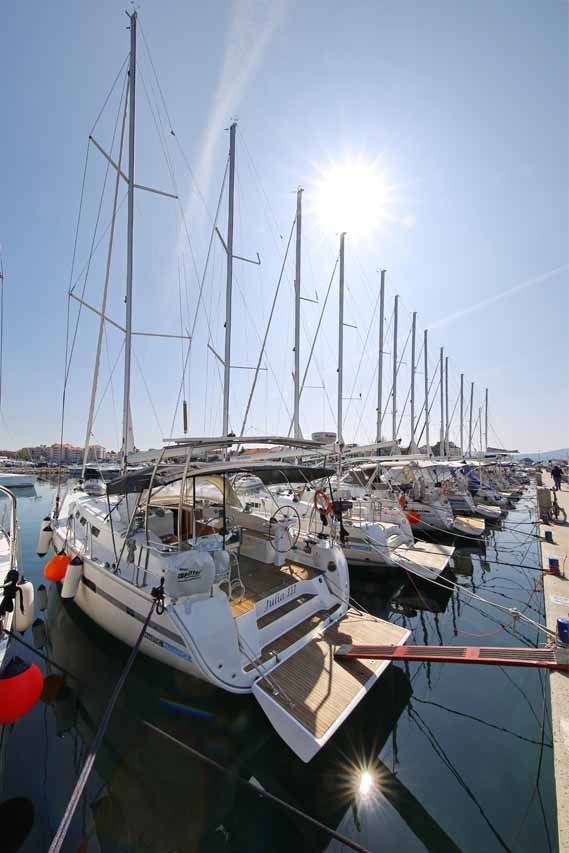 Luxury yachts docked at a prestigious marina under bright sunlight, showcasing Julia III prominently.