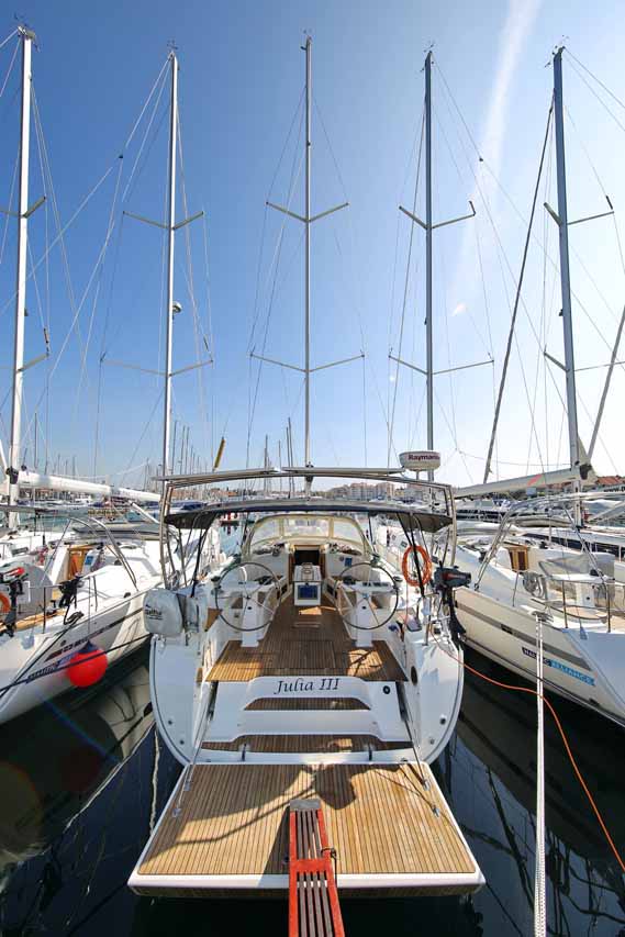 Sleek profile of Julia III docked in a vibrant marina, showcasing its elegant design and spacious deck.