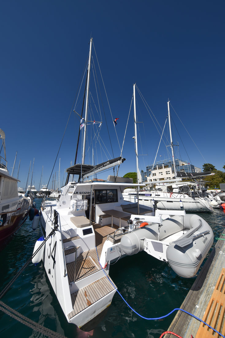 Lauremi docked in a vibrant marina, showcasing sleek lines and inviting outdoor space.