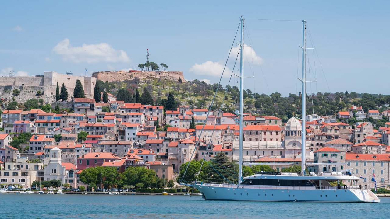 M/S Aurum Sky anchored near a picturesque coastal town with vibrant rooftops and historic architecture.