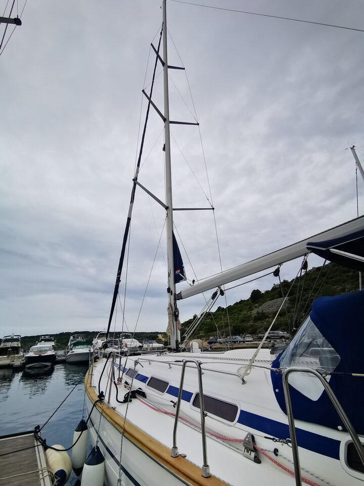 Elegant profile of Sea Gull docked in a serene marina, showcasing its sleek mast and hull design.