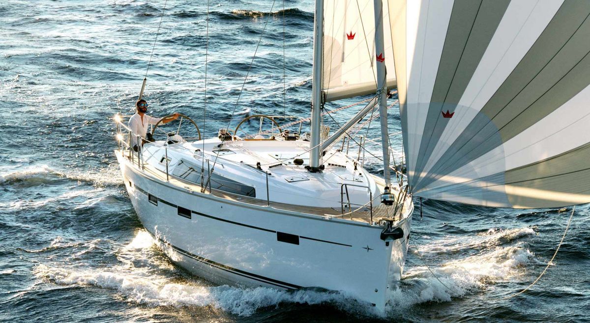 Sleek profile of Rebel Rebel sailing gracefully through shimmering waters with billowing sails.