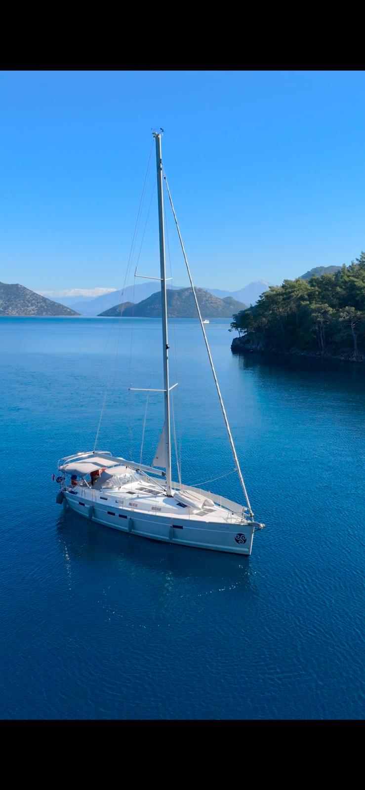 Shoogle gracefully sailing in tranquil waters, surrounded by lush hills and clear blue skies.