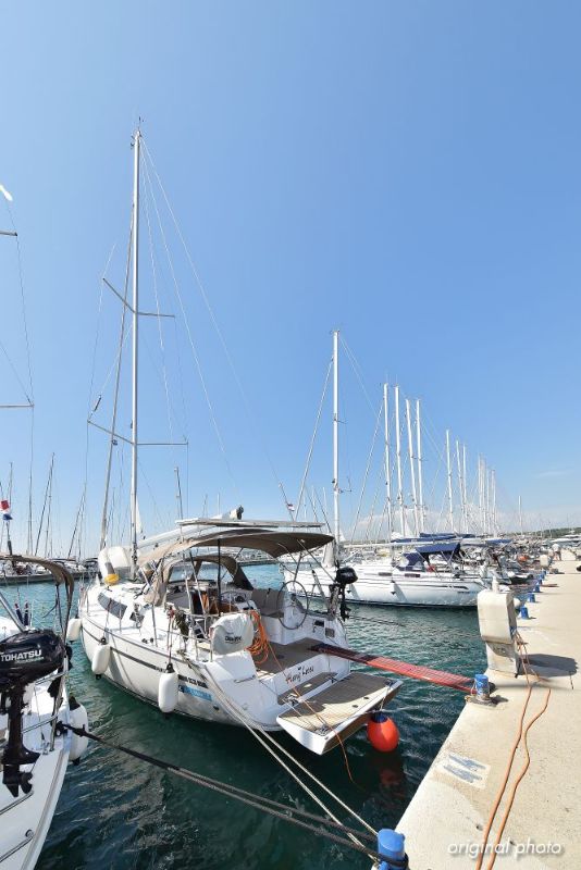 Luxury yacht Hang Loose docked in a vibrant marina under a clear blue sky.