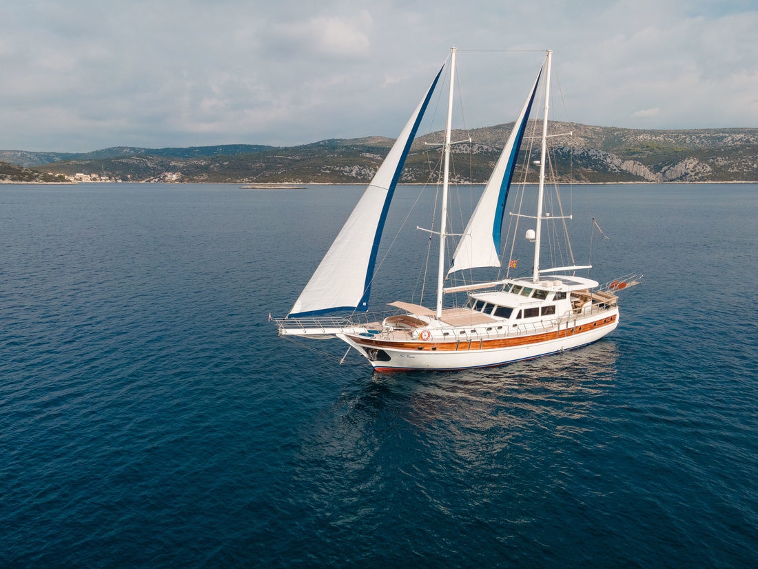 Elegant sailing yacht Sea Breeze gliding through calm waters with billowing sails.