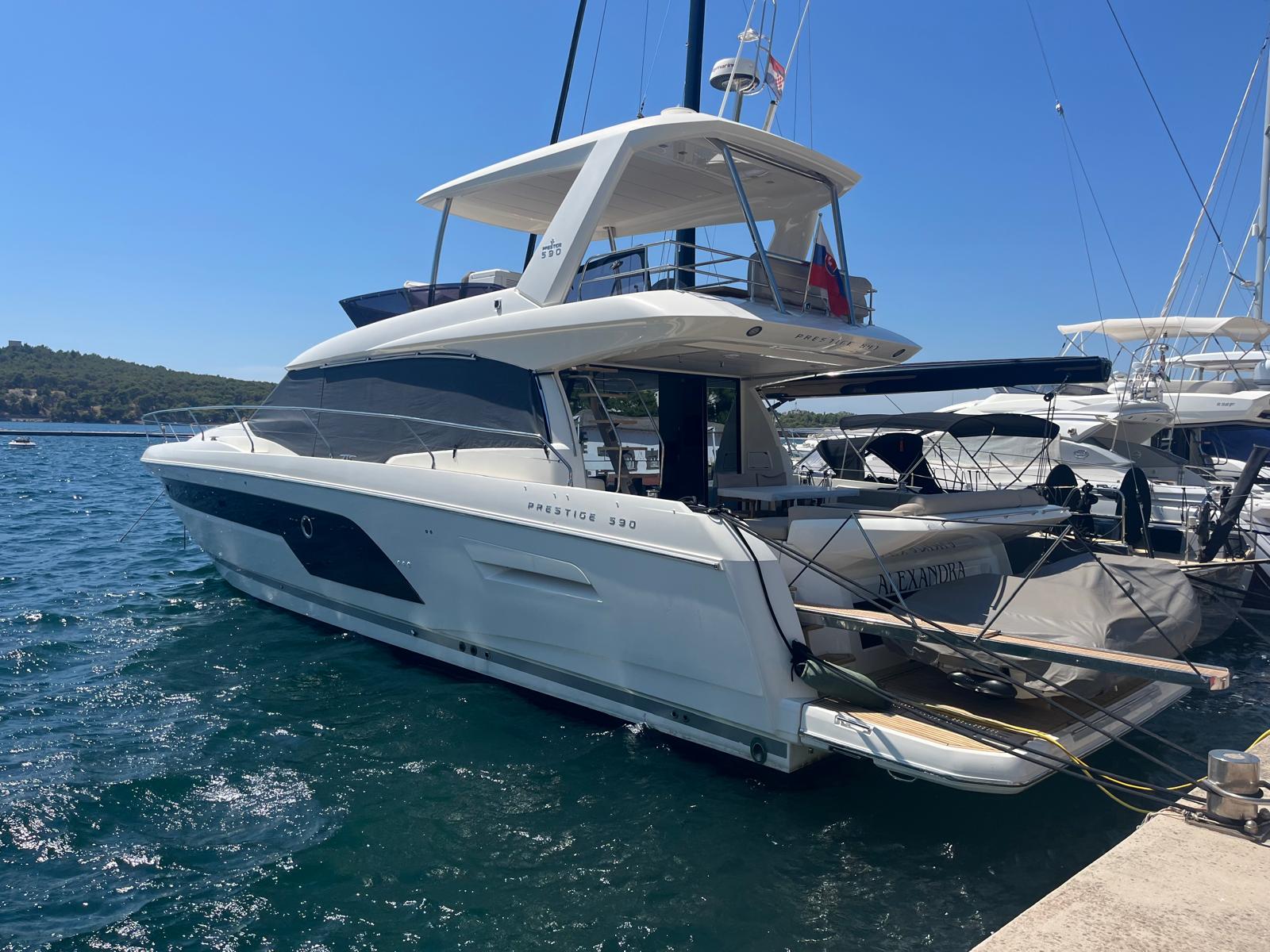 Sleek profile of the 590 Fly 2021 gliding through crystal-clear waters at a prestigious marina.