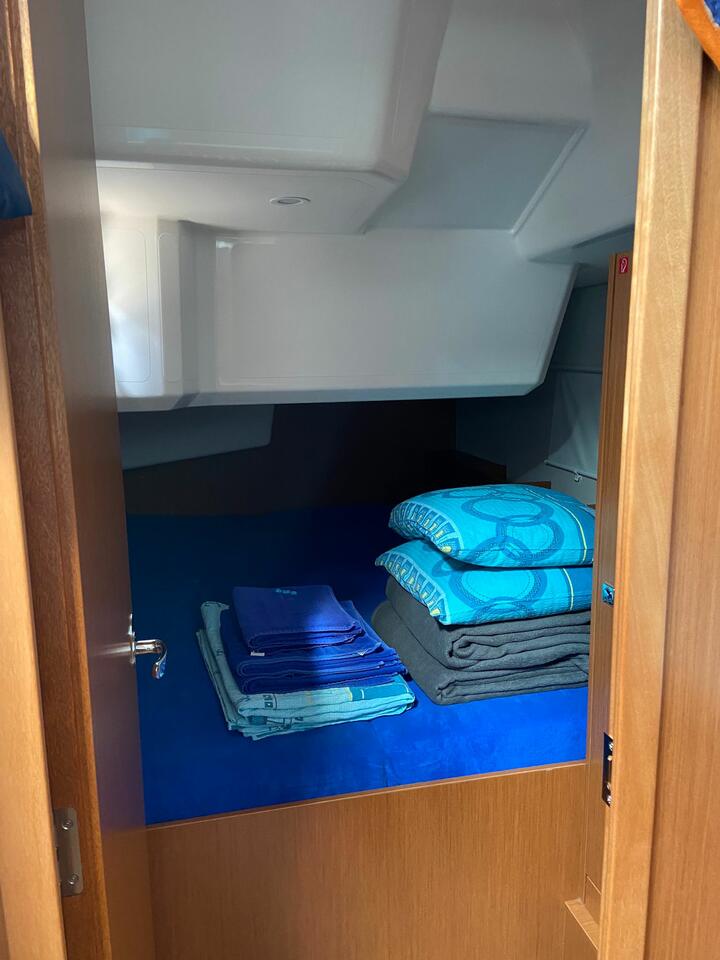 Cozy cabin aboard La Vela featuring neatly arranged blue linens and warm wooden accents.