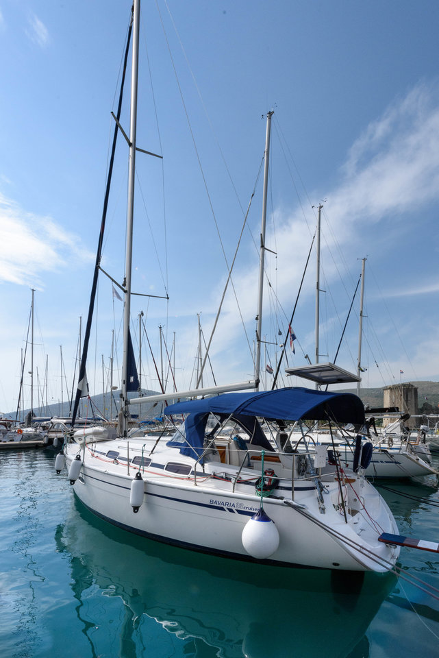 Elegant Dišpet docked at a marina, showcasing its sleek hull and vibrant blue canopy.