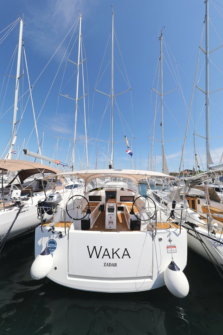 Sleek stern view of Waka showcasing elegant lines and luxurious teak details in marina.