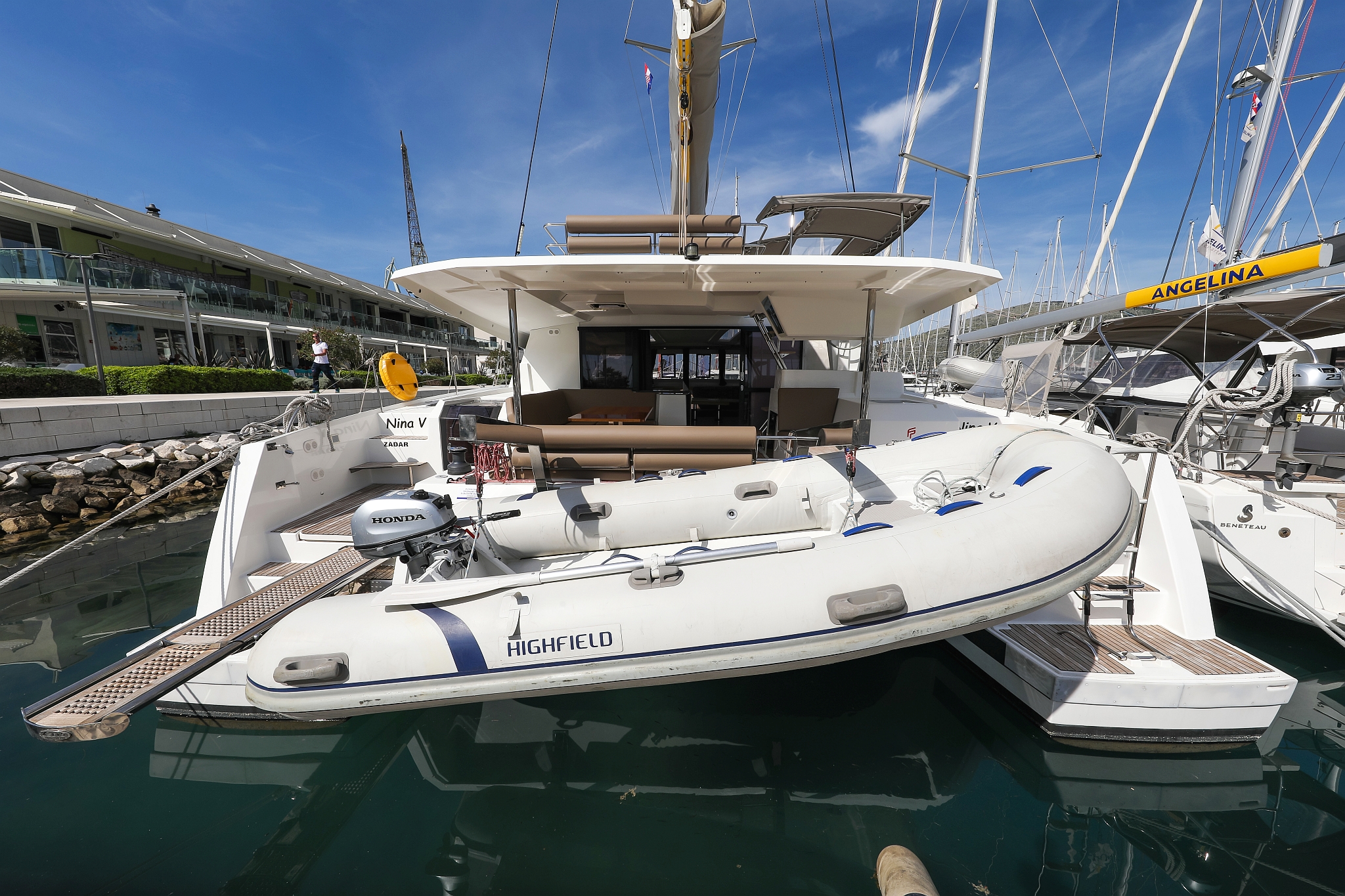 Nina V. showcases a sleek profile with elegant lines and a luxurious tender at the marina.