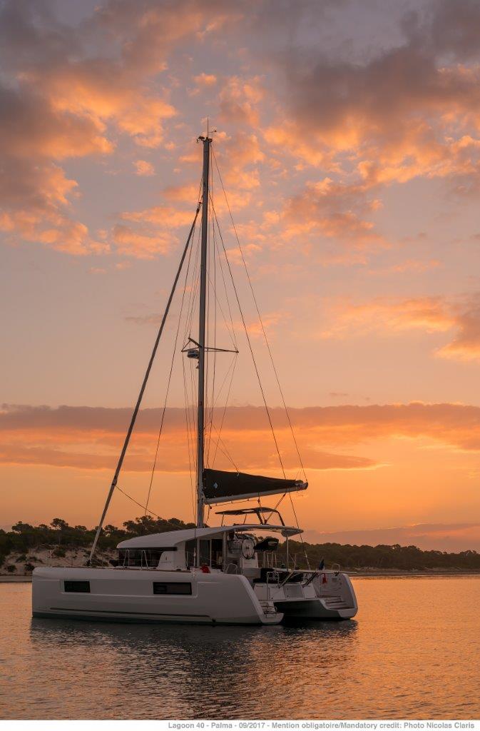 Elegant silhouette of the Korina yacht against a stunning sunset backdrop.