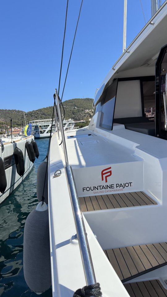 Sleek profile of My Precious "E" showcasing Fountaine Pajot branding at a vibrant marina.