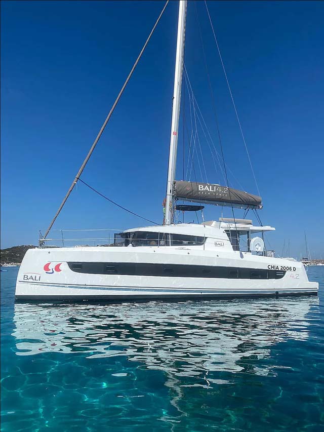 Sleek profile of Arveskida II gliding across crystal-clear waters under a bright blue sky.