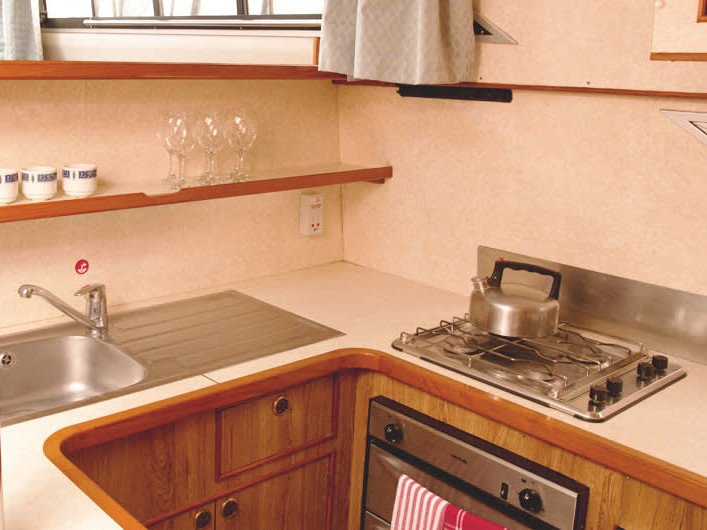 Sleek, well-equipped galley on Clipper - Comfort 13 featuring warm wood accents and modern appliances.