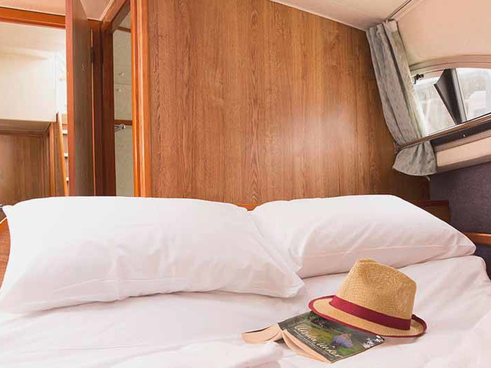 Luxurious cabin on Clipper - Comfort 25 featuring elegant wood finishes and cozy bedding.