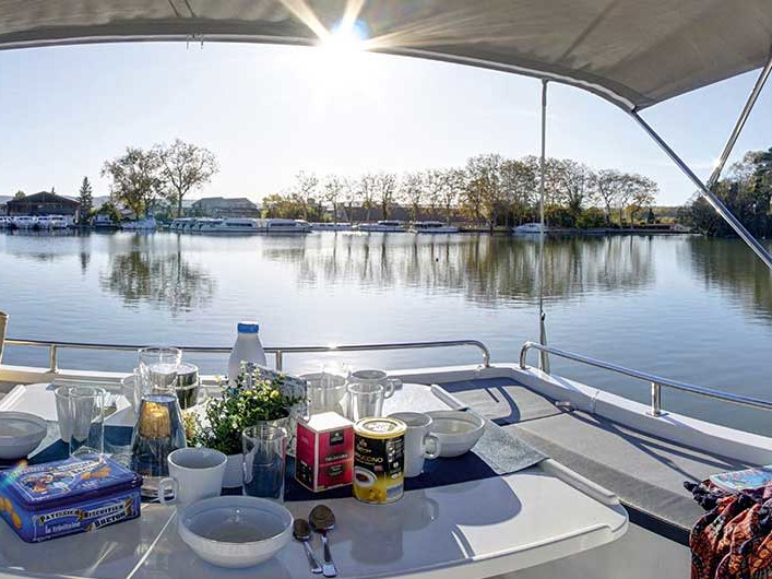 Elegant dining setup on Horizon 2 - Premier 14, overlooking serene waters and lush greenery.