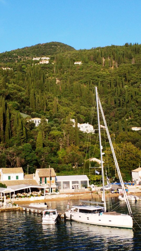Freedom anchored in a picturesque marina surrounded by lush greenery and charming coastal homes.