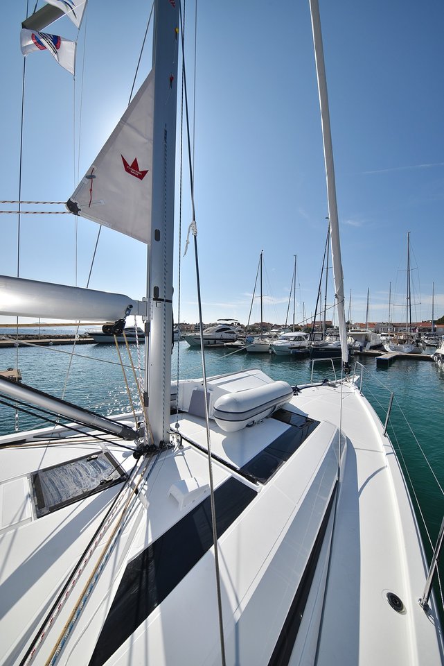 Sleek profile of Antonela M. docked in a vibrant marina under clear blue skies.