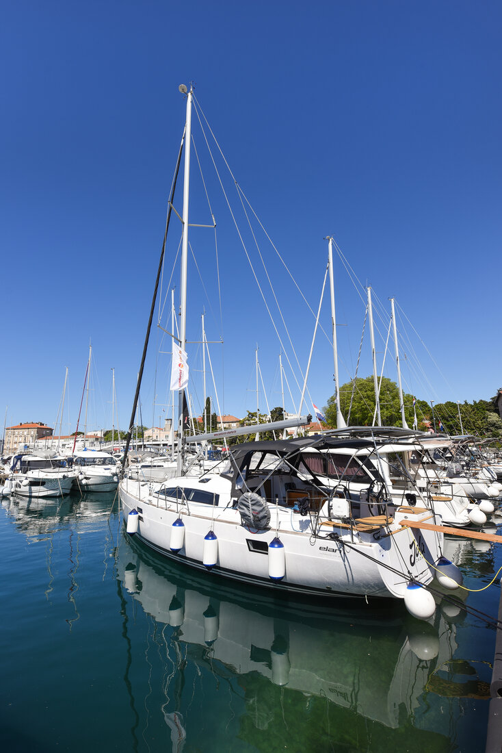 Sleek profile of the Jola docked in a vibrant marina under clear blue skies.